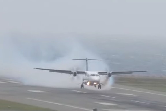 Front-on view of an Air New Zealand ATR72-600 twin-turboprop aircraft (ZK-MVL) on final approach to Wellington Airport on 1 September 2024. The plane is low over the runway with its landing gear down but not yet touched down. Dense grey-white smoke billows from the left engine, trailing back behind the aircraft, with the sea visible in the hazy overcast background beyond the runway