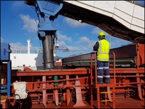 Photo in SWMS showing the signalman standing on a pedestal looking over the hatch coaming into the hold