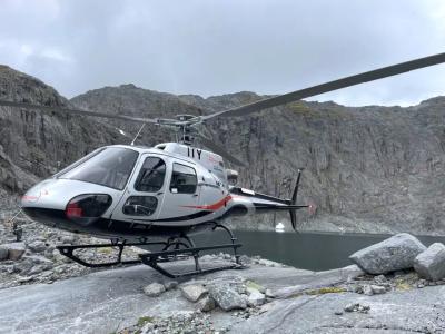 Photo of a Aérospatiale AS350B3 Ecureuil stationary on the ground in a rocky mountain environment 