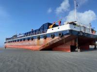 The barge lies embedded in the beach 